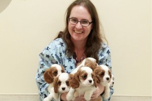 Dr. Terri Pettis, owner and passionate pet-lover, is captured in her element, surrounded by a group of adorable puppies.